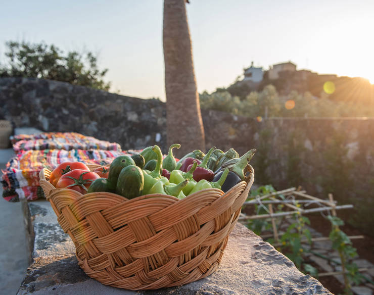 Basket of fresh garden vegetables on a stone wall at Elounda Naxia Villas, with the sunset in the background