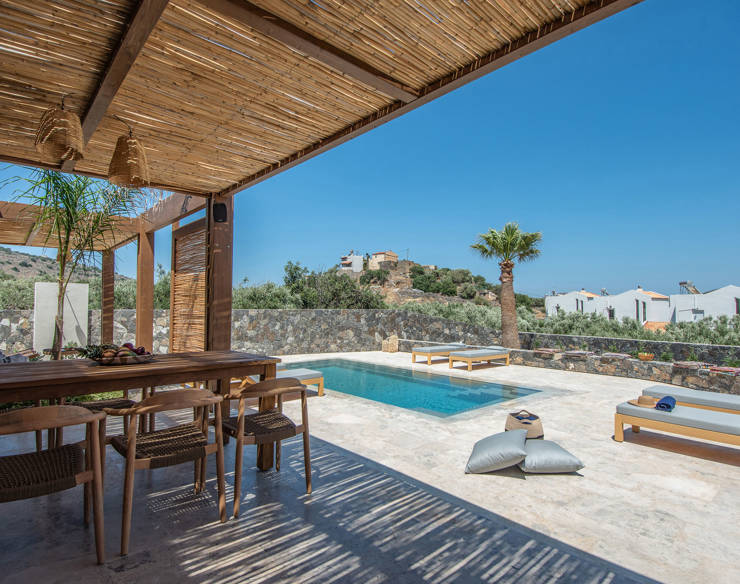Covered outdoor dining area with wooden pergola, and view of the private pool with sun loungers and olive trees