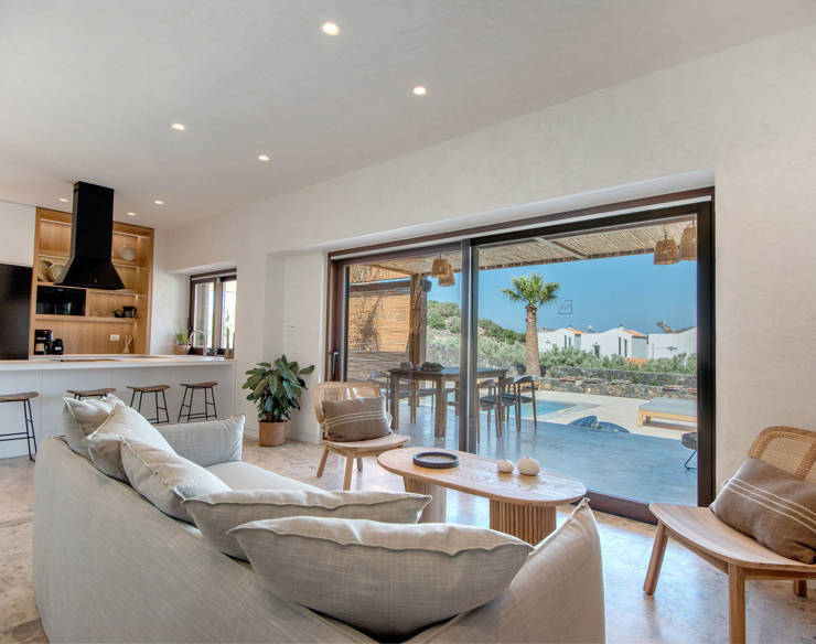 Bright living area at Elounda Naxia Villas with cozy furniture, and large glass doors accessing the terrace