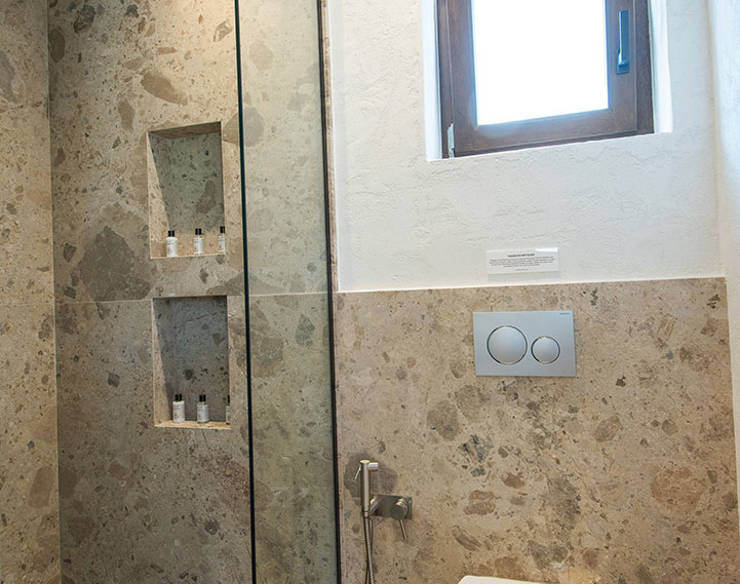 Contemporary bathroom at Elounda Naxia Villas with stone walls, walk-in shower, and natural light window