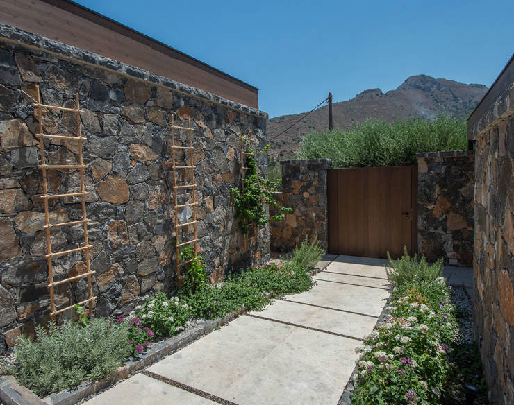 Stone garden walkway at Elounda Naxia Villas with climbing plants, flowers, and mountain view