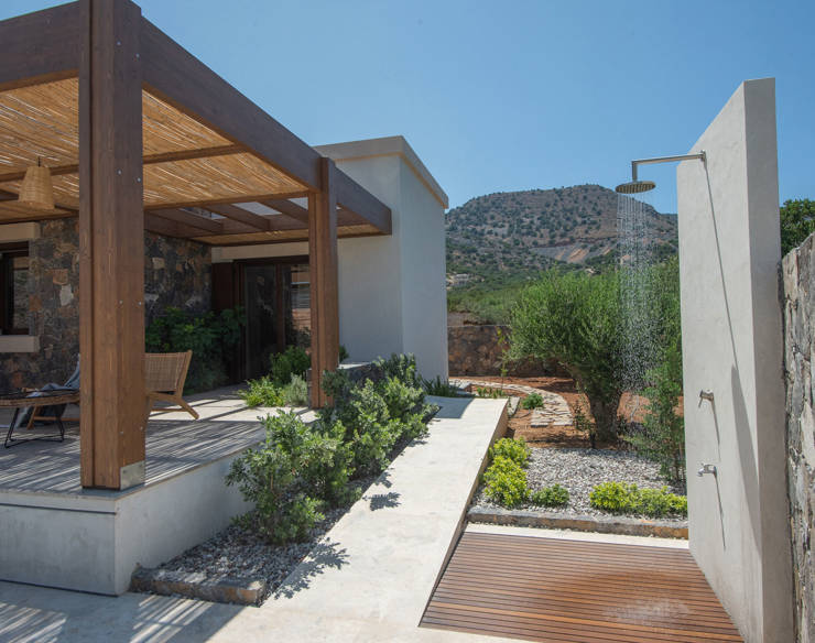 Outdoor shower and shaded terrace at Elounda Naxia Villas with stone walls, garden and mountain view