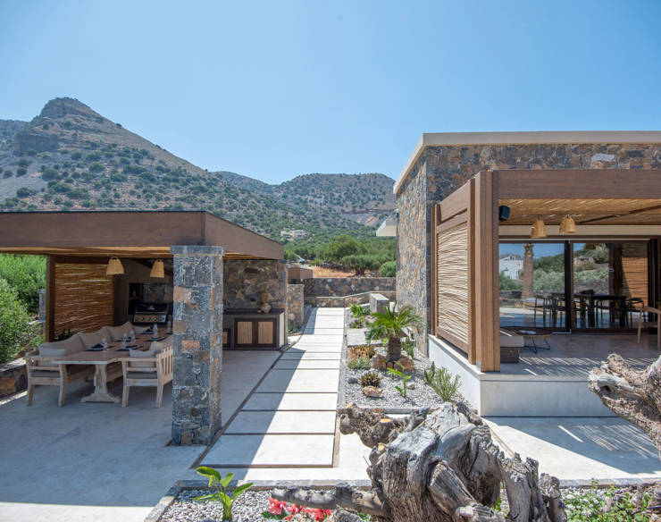 Outdoor view of Elounda Naxia Villas showing a stone terrace with shaded dining and BBQ area