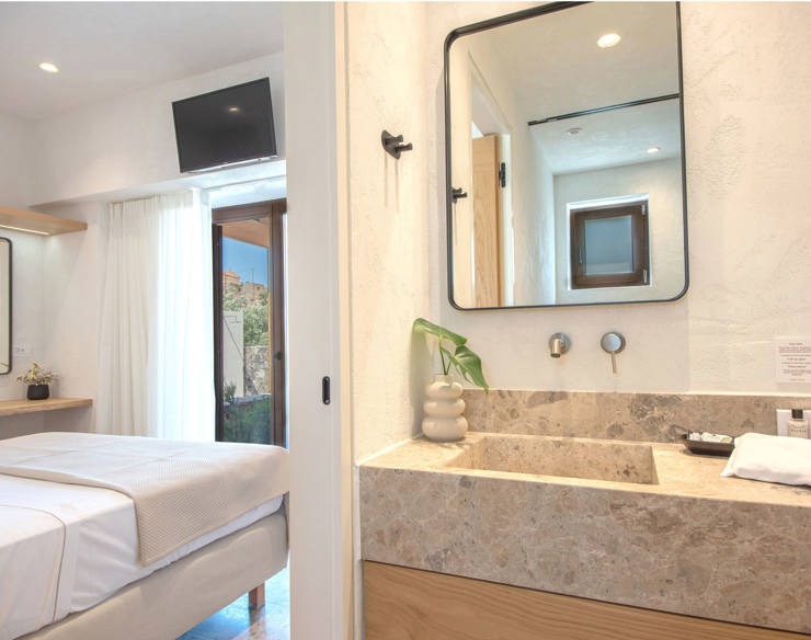 Bright master bedroom and ensuite bathroom a Elounda Naxia Villas with marble sink and patio view