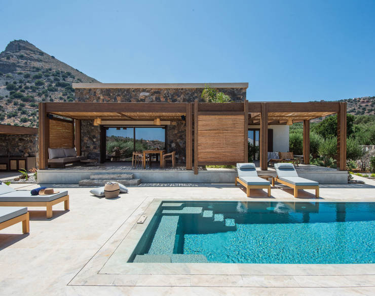 Elegant private pool with shaded sunbeds, shaded lounge areas and mountain views at Elounda Naxia Villas