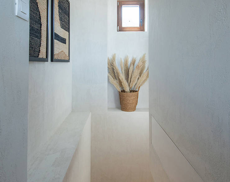 Minimalist staircase at Elounda Naxia Villas with wooden steps, wall art, and natural light from a small window