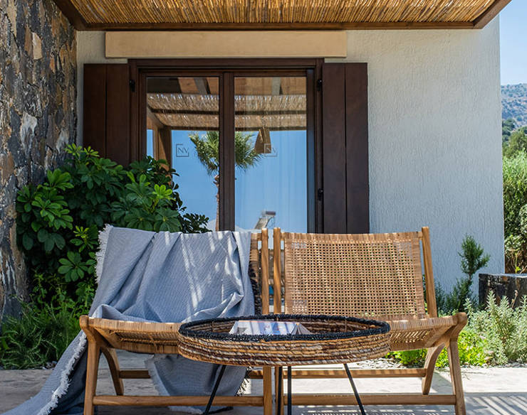 Cozy outdoor sitting area at Elounda Naxia Villas with rattan chairs, small table, and shaded pergola