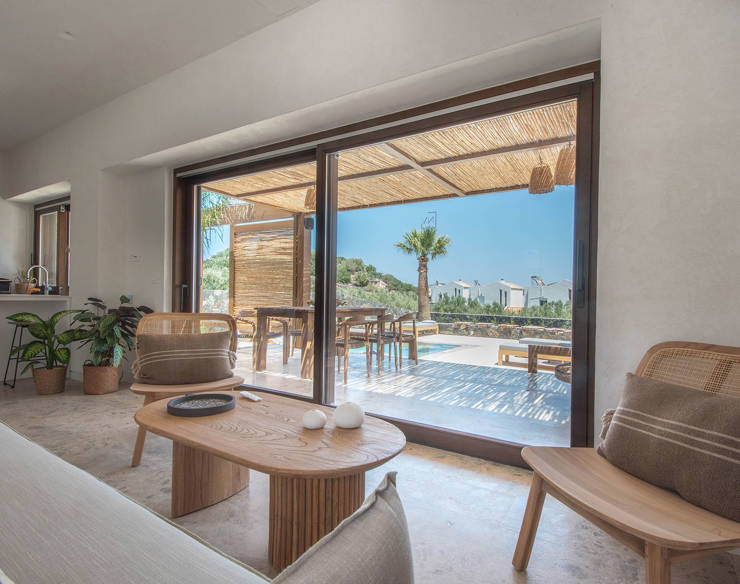 Bright living room at Elounda Naxia Villas with wooden furniture, soft tones, and glass doors