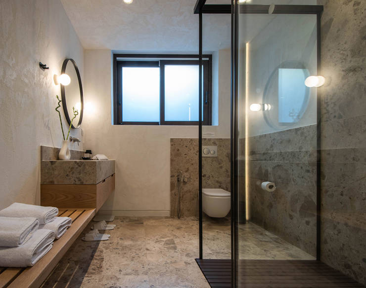 Elegant bathroom at Elounda Naxia Villas with stone surfaces, glass shower, and soft ambient lighting