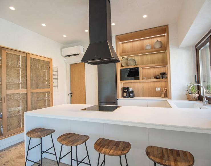Bright modern kitchen at Elounda Naxia Villas featuring a central island with stools, and natural wood finishes