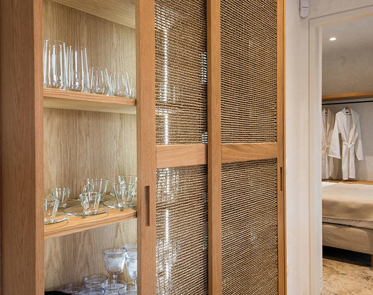 Wooden cabinet with woven sliding doors, displaying neatly arranged glassware and tableware on open shelves