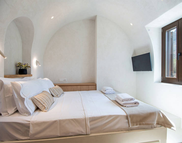 Bright bedroom at Elounda Naxia Villas with arched ceiling, cozy double bed, and mountain view