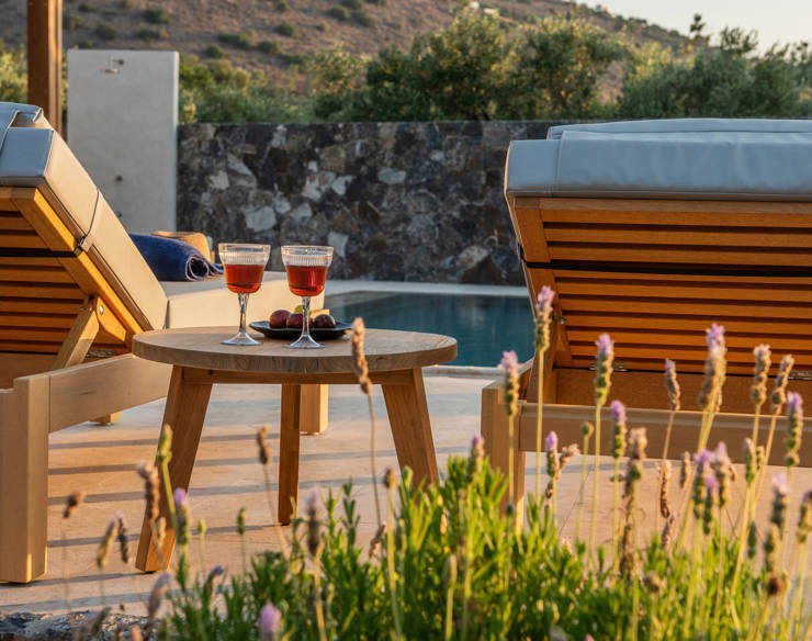 Two wooden loungers by the pool with a small round table, surrounded by blooming lavender 