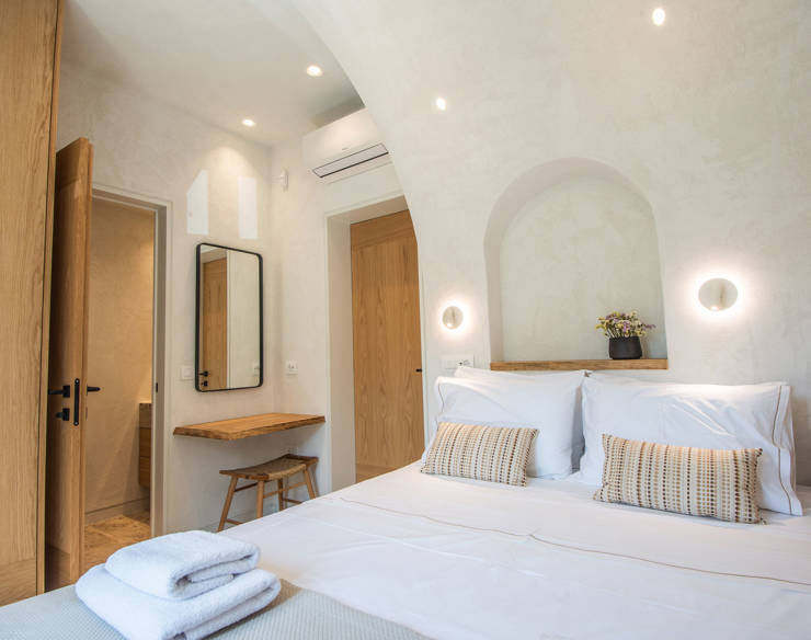 Cozy bedroom at Elounda Naxia Villas with arched ceiling, double bed, wooden furniture, and soft ambient lighting
