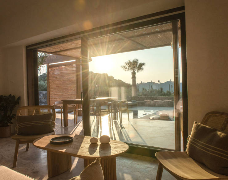 Sunset view from the living area of Elounda Naxia Villas, with cozy wooden furniture and sliding glass doors