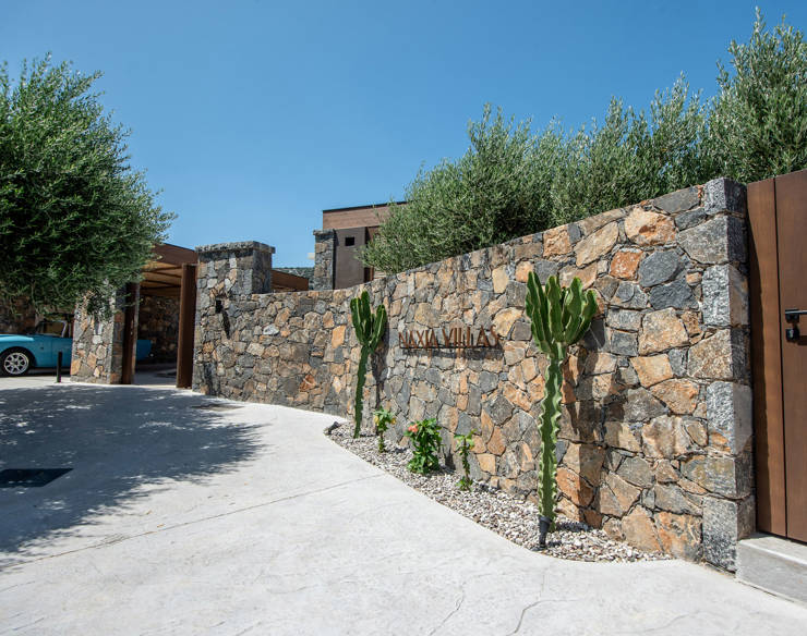 Stone entrance of Elounda Naxia Villas with cactus plants and a vintage car under a clear blue sky