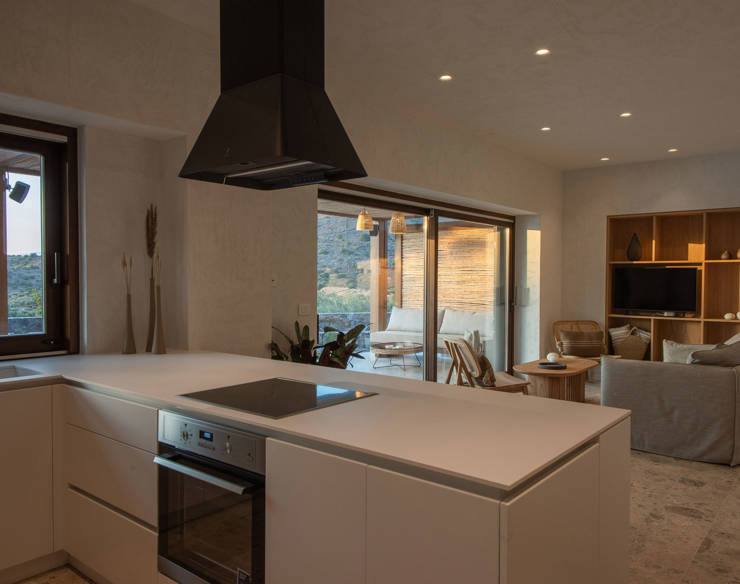 Open-plan kitchen and living area at Elounda Naxia Villas with modern cabinetry, large windows, and cozy seating