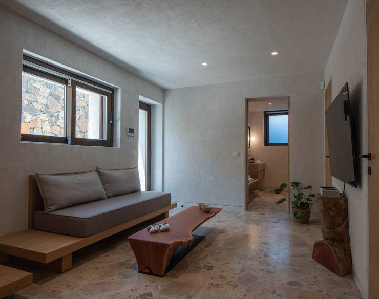 Elegant lower-level living area at Elounda Naxia Villas with minimalist decor, stone floor and wooden furniture