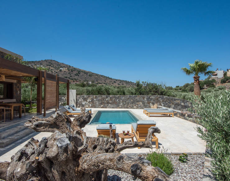 private pool at Elounda Naxia Villas surrounded by sun loungers, stone walls and Mediterranean garden