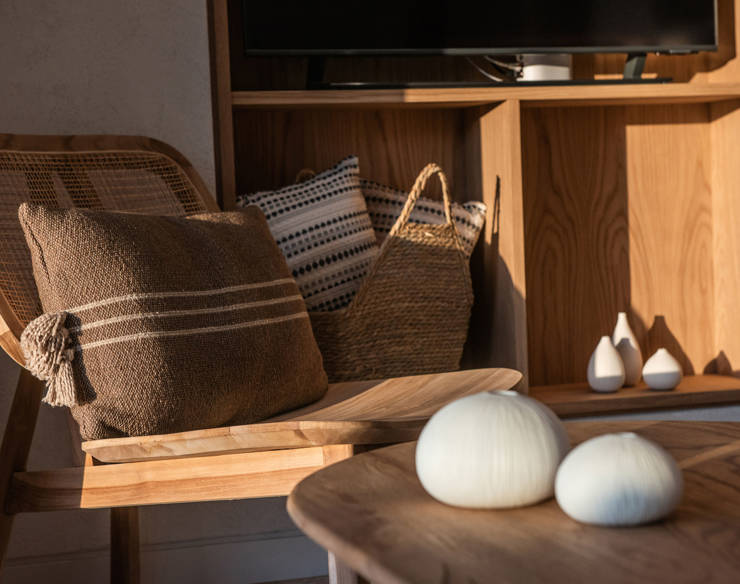Close-up of a seating corner at Elounda Naxsia Villas with a wooden chair, cushion, and decorative vases