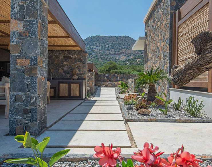 Colorful garden path at Elounda Naxia Villas with stone walls, tropical plants, and mountain backdrop