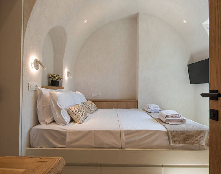 Elegant bedroom at Elounda Naxia Villas with arched ceiling, soft lighting, and neatly arranged linens