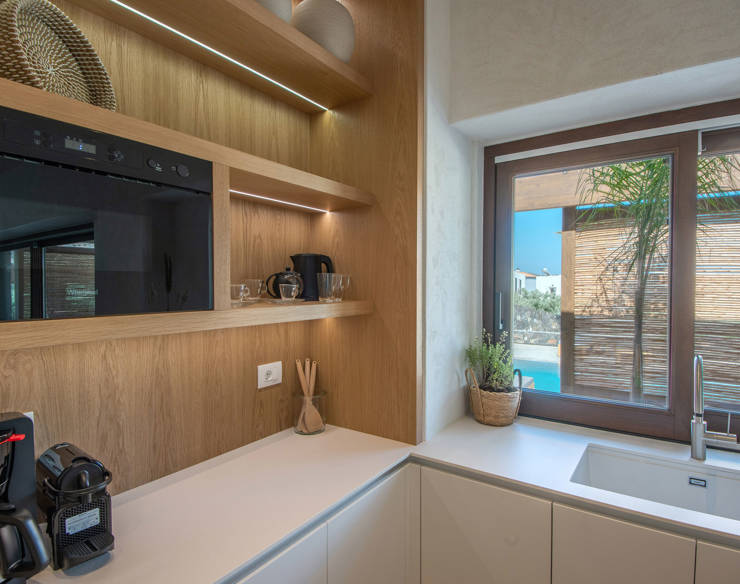 Bright kitchen at Elounda Naxia Villas with open wooden shelves, coffee machine and large windows