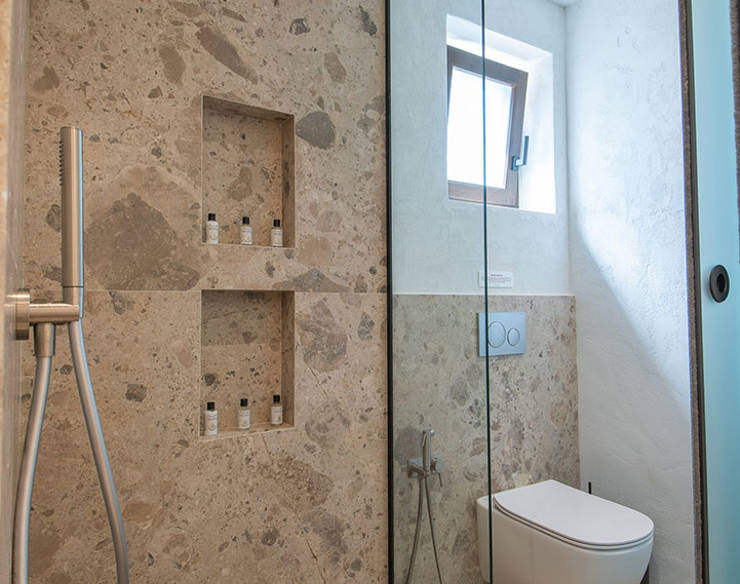 Stylish bathroom at Elounda Naxia Villas with stone walls, walk-in shower, and glass partition
