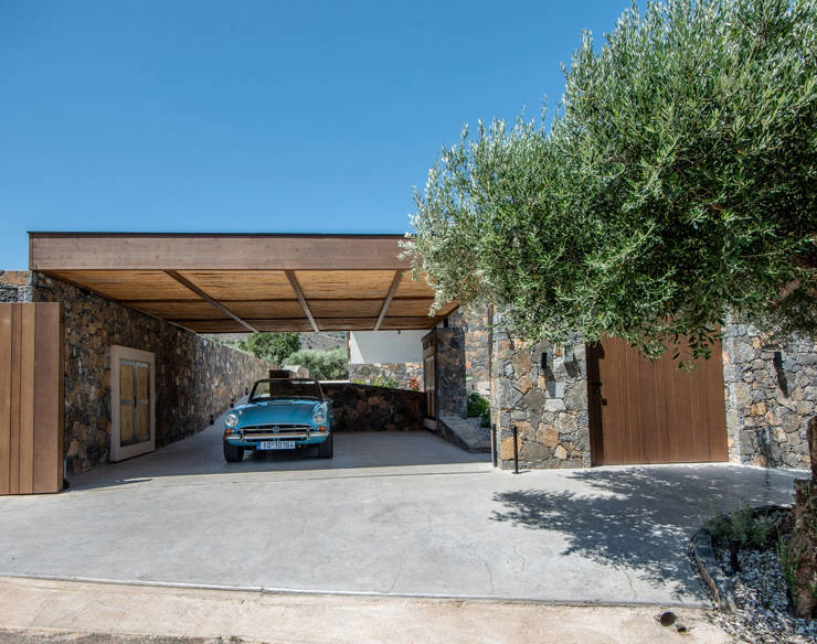 Garage area of Elounda Naxia Villas with stone walls, wooden roof, and a vintage blue convertible car