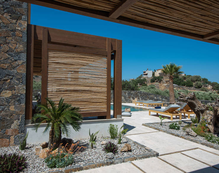 Mediterranean garden at Elounda Naxia Villas with palm trees, stone paths, and view of the pool area